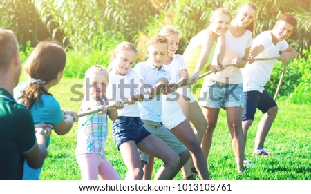 Glad Kids With Moms And Dads Playing Tug Of War During Joint Outdoors Games On Sunny Glad Kids With Moms And Dads Playing Tug Of War During Joint Outdoors Games On Sunny