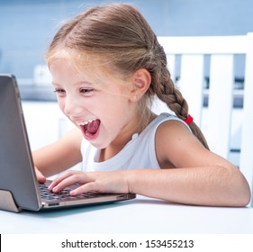 glad little girl with her computer at home at the table