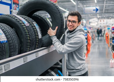 Glad Male Customer Buying New Tires In The Supermarket. He Looks Happy