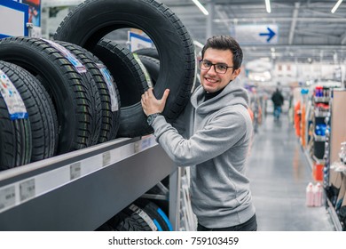 Glad Male Customer Buying New Tires In The Supermarket. He Looks Happy