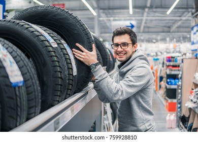 Glad Male Customer Buying New Tires In The Supermarket. He Looks Happy