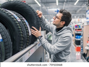 Glad Male Customer Taking New Tires In The Supermarket For Buying. He Looks Happy. Big Shopping Mall With Car Goods.