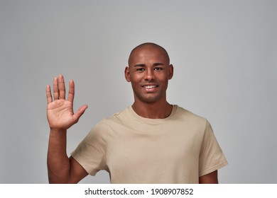 Glad man putting his right hand up in the air with an open palm and smiling