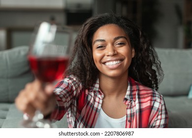 Glad Millennial African American Lady With Glass Of Wine Cheers At Camera, Have Video Call In Living Room Interior, Close Up. Date, Birthday And Anniversary Remotely At Home, Holiday Celebration