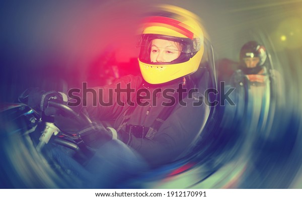 Glad positive smiling woman driving\
sport car for karting in a circuit lap in sport\
club