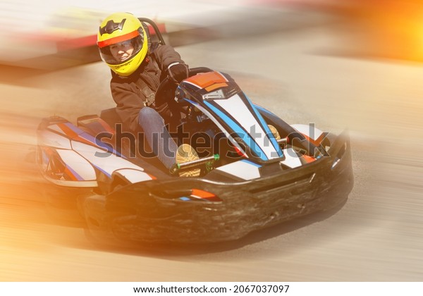 Glad positive smiling woman\
driving sport car for karting in a circuit lap outdoor in sport\
club