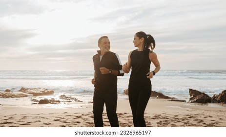 Glad senior caucasian family in sportswear jogging, enjoy training and active lifestyle on beach in morning, outdoor, panorama. Body care, relationships, weight loss together - Powered by Shutterstock