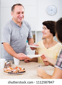 Glad Senior Man Setting Table For Family Lunch At Home Indoors