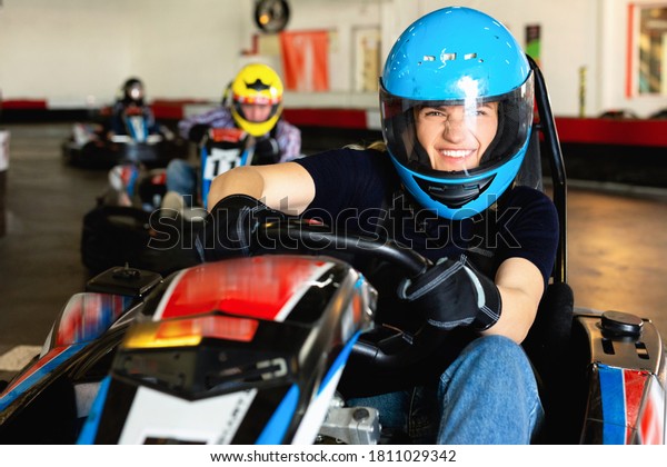 Glad smiling woman and her friends competing on\
racing cars at kart\
circuit