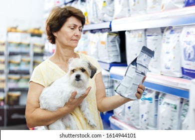 Glad Woman Choosing Dog Food For Her Puppy In Pet Supplies Store