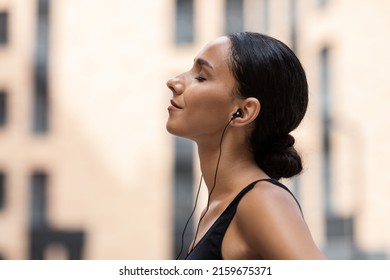 Glad Young Arab Female With Closed Eyes In Headphones Enjoy Music And Relaxing On Building Background Outdoor, Profile, Close Up. Sports On Street With Device, Weight Loss, Body Care And Training