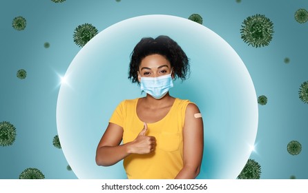 Glad Young Black Female In Mask Shows Shoulder With Band Aid After Vaccination And Thumb Up, In Bubble, Protecting From Viruses On Blue Background. Covid-19 Or Flu, Antiviral Injection To Patient