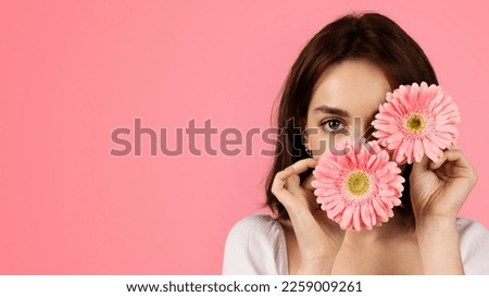 Glad young european woman putting flowers to her face, has fun in free time, enjoy tenderness, isolated on pink background, studio, close up. Holiday, beauty and health care, spa day, ad and offer