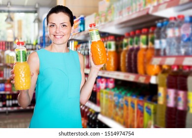 Glad Young Woman Choosing Fruit Juice On Supermarket Shelf 