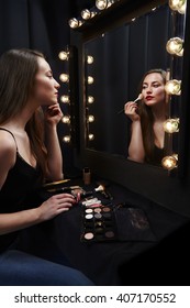 Glamorous beauty applying make up in mirror