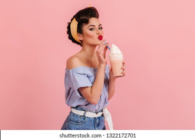 Glamorous caucasian woman drinking milkshake. Studio shot of fashionable brunette girl posing with cocktail on pink background. - Powered by Shutterstock