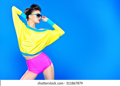 Glamorous fashion model posing in vivid colourful clothes and sunglasses. Bright fashion. Optics, eyewear. Studio shot.