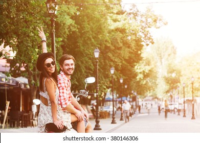 glamorous happy young couple riding  a vintage scooter in the street, woman wears a hat and sunglasses - Powered by Shutterstock