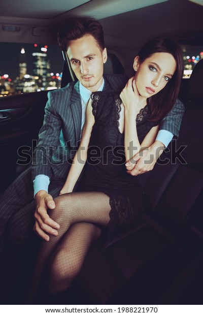 Glamorous lifestyle.\
Fashionable couple of young people in the car are driven through\
the city at night. 