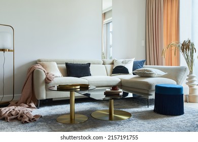 Glamorous living room interior design with modern beige sofa, glass coffee table, red armchair and golden accessories. Template. 
