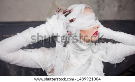 Glamorous mummy. Portrait of a young beautiful woman in bandages all over her body. Halloween or plastic surgery concept