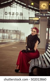 Glamorous retro girl at the train station in a red dress.Portrait of a beautiful girl. Vintage. Retro. Pin Up. Beautiful make-up and hairstyle in a classic style. Railway station. 