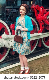 Glamorous retro girl in train in a vintage dress.Portrait of a beautiful girl. Vintage. Retro. Pin Up. Beautiful make-up and hairstyle in a classic style. Railway station. 