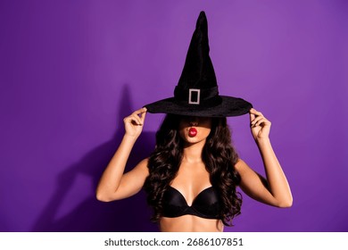 Glamorous witch in a stylish hat posing confidently against a vibrant purple backdrop, embodying Halloween spirit and fashion