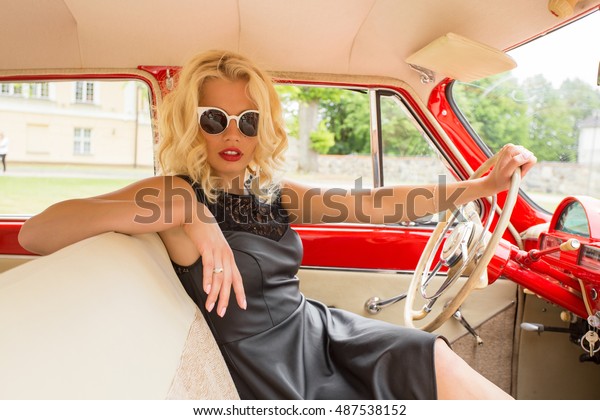 Glamorous woman driving a\
vintage car