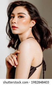 Glamorous young asian woman with black hair and Beautiful Professional Makeup. wearing black Sexy Tops Vest. She is posing sexy with white background. Haircare, Skincare, Sunscreen, party concept.