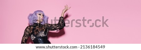 glamour drag queen in purple wig pointing with finger on pink, banner