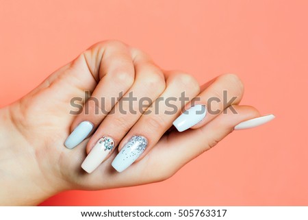 glamour female hand and fingers with fashionable trendy nail polish white color on fingernails has soft skin of young human on orange background, closeup