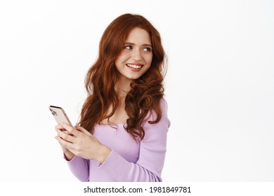 Glamour Girl With Ginger Hair Turn Around To Smile At Promo Offer, Chatting On Mobile Phone, Holding Smartphone To Message Or Use Application, White Background