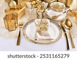 Glamour style Christmas table setting in white and gold colors with elegant porcelain tableware 