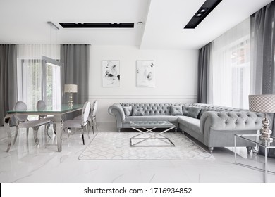 Glamour style white and gray living room with quilted corner sofa and elegant glass coffee and dining table