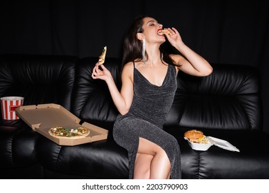 Glamour Woman Eating French Fries Near Pizza And Burger On Leather Couch Isolated On Black