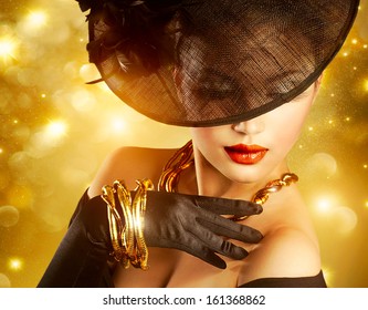 Glamour Woman Portrait Over Holiday Gold Background.Luxury Golden Jewelry. Gorgeous Vogue Style Lady Wearing Hat And Gloves. Jewellery. Vintage Styled Retro Girl 