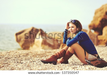 glamourous portrait of the young beautiful woman  in leather boots on the bank of a beach