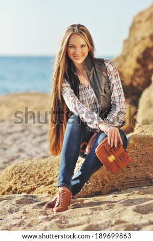 glamourous portrait of the young beautiful woman in leather boots on the bank of a beach