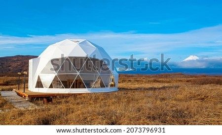 Glamping house in summer and volcano, rural landscape, tent houses in Kamchatka peninsula. Selective focus.