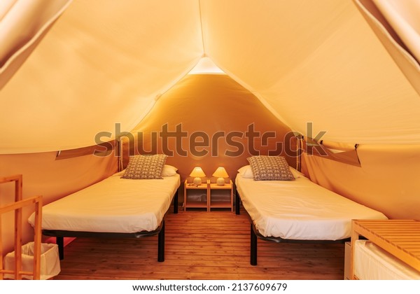 Glamping tent cozy interior with beds on a sunny\
day. Glamorous camping tent for outdoor summer holiday and vacation\
lifestyle concept