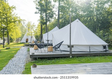 Glamping tents in a serene forest setting with wooden decks and outdoor seating - Powered by Shutterstock