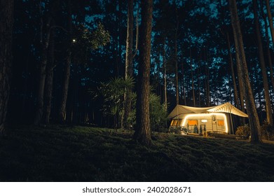 Glamping tourist vacation in Pine Forest Park on night sky in the background with LED warm light with Copy space. Add the Realistic Film Color Tone and Grain. - Powered by Shutterstock