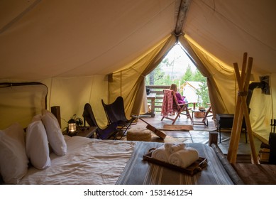 glamping trip - woman sitting outside luxury camping tent enjoying view of forest