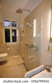 
Glance into a bathroom with a modern minimalist shower. The tiles are beige and shiny