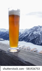 Glas of hell natuurtrub weiss beer in the alps on wooden fence