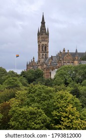 Glasgow Scotland UK - August 19 2017: LGBT flag hoisted in front of the great tower of the St Andrew's University in Glasgow, during cloudy day, with canopies of trees in the foreground
