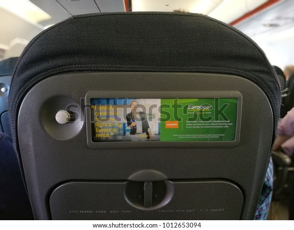 Glasgow, UK - 29 January\
2018 : an adveristement of a hire car company on the back of the\
plane seat. 