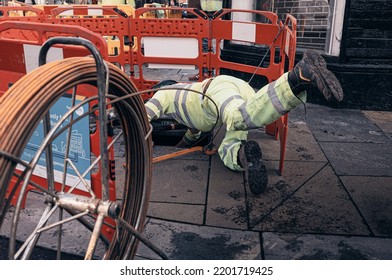 GLASGOW, UNITED KINGDOM - Oct 04, 2021: A Manual Worker Wearing Uniform Fixing Water Pipes In Manhole