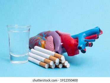 A Glass Of Alcohol And A Bunch Of Cigarettes With A Heart Organ On A Blue Background. The Concept Of Bad Habits Badly Affecting Health And Cardiovascular Systems, Close-up